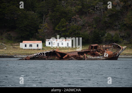 Ushuaia, Argentine - le 27 mars 2019 : Le bateau monte Sarmiento en contrebas d'un accident contre un rocher en 1912. À l'arrière, une ferme abandonnée appelée El R Banque D'Images