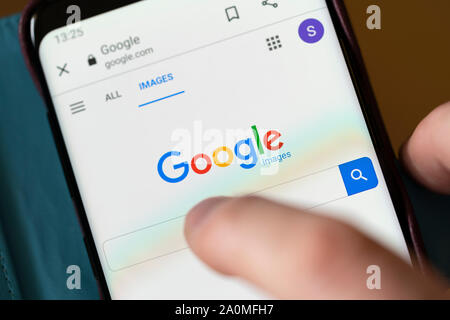 Un homme sur le point de faire une recherche sur une barre de recherche Google Images sur un smartphone Banque D'Images