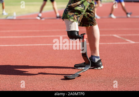 Athlète Paraolympic avec prothèse remplit à l'exécution sur la piste du stade avec d'autres personnes sur background.homme fort avec formation membre amputé Banque D'Images