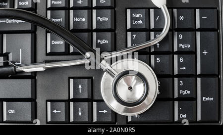 Vue de dessus du stéthoscope sur noir clavier de l'ordinateur dans une image conceptuelle. Banque D'Images