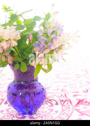 Vase bleu avec des fleurs sauvages sur la table avec une nappe rouge Banque D'Images