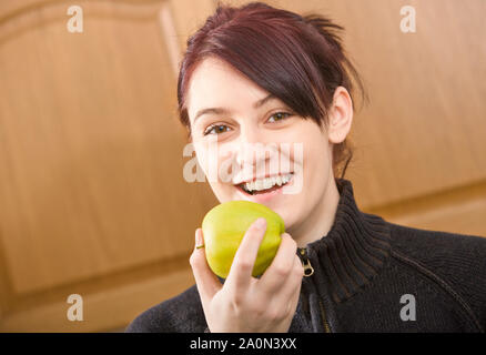 Jeune femme de manger une pomme à l'intérieur Banque D'Images