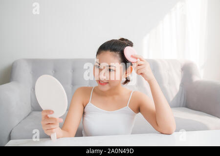 Young Asian woman peigner les cheveux et à la recherche dans le miroir Banque D'Images