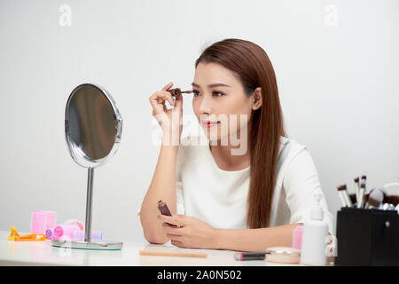 Modèle de beauté adolescente à la recherche dans le miroir et le mascara maquillage. Belle jeune femme maquiller Banque D'Images