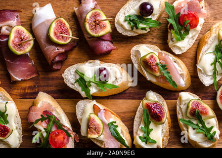 Assortiment de brushetta - italien apetizer ou des tapas espagnoles traditionnelles pour le partage. Cuisine de fête sur le plateau de restauration. Antipasti avec de la viande, du fromage et des fruits Banque D'Images