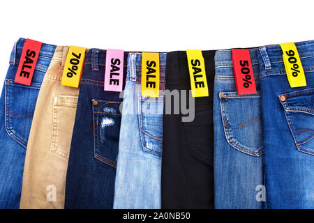 Vente boutique de vêtements, des remises, des jeans de différentes couleurs bleu, vert, noir sur fond blanc isolated close up Banque D'Images
