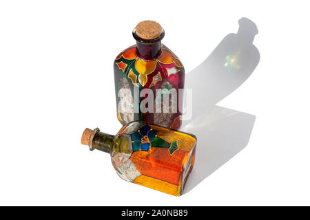 Bouteilles en verre de couleur avec du sable à l'intérieur isolé sur fond blanc Banque D'Images