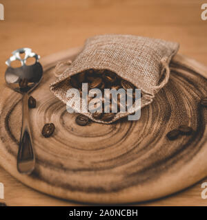 Pochette de grains de café et cuillère à café en forme de crâne assise sur une planche ronde en bois Banque D'Images