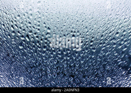 La fenêtre de verre dans les gouttes de pluie, beau dégradé bleu couleur avec l'eau, miroir embué surface texture background close up Banque D'Images