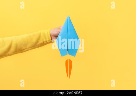 Hand holding paper plane sur fond jaune Banque D'Images