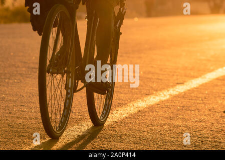 Libre de vélo roues/pneus sur une route asphaltée au Mozambique au lever du soleil, d'être monté au travail le matin. La ville de Nampula, au Mozambique Banque D'Images