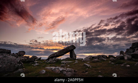 Le soleil se couche sur St David's Head dans le Parc National de Pembrokeshire, silhouetting la chambre funéraire néolithique de Arthur's Quoit. Banque D'Images