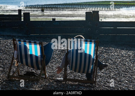 Un couple profitez de la dernière du soleil sur la plage de Margate sur la côte du Kent à la fin de l'été Banque D'Images