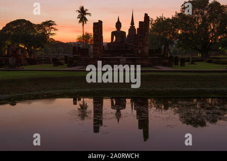 Sculpture d'un Bouddha assis sur les ruines d'un temple bouddhiste Wat Chana Songkram sur fond coucher de soleil. Le parc historique de Sukhothai, Thaïlande Banque D'Images