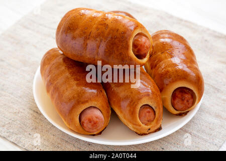 Saucisse de boeuf maison kolache sur une plaque blanche sur un fond de bois blanc, vue de côté. Close-up. Banque D'Images