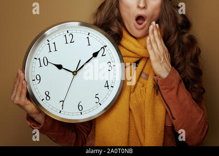 Gros plan sur la mode femme choqué en béret et écharpe jaune avec horloge ronde d'oublier le temps d'automne changement sur fond brun. Banque D'Images