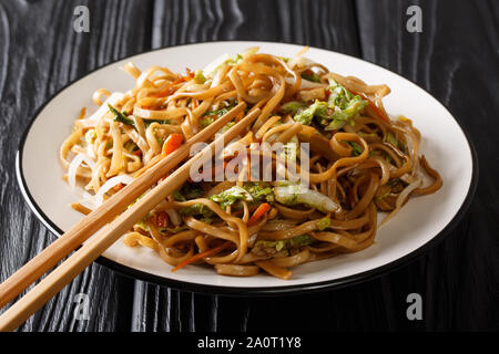 Chinois classique poêlée de nouilles chow mein aux légumes close-up sur une plaque sur la table horizontale. Banque D'Images