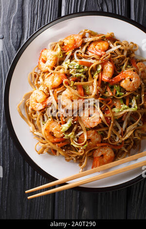 Portion de nouilles chow mein aux crevettes et légumes close-up sur une plaque sur la table. Haut Vertical Vue de dessus Banque D'Images