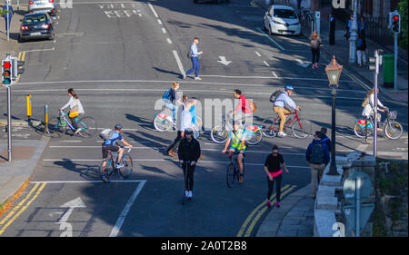 Les banlieusards au travail à vélo sur des vélos, des vélos en piste cyclable. Personne sur scooter électrique et de charge du véhicule électrique. Dublin, Irlande Banque D'Images