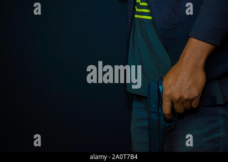 Asian man détient une arme à feu. Fusil à la main isolé sur fond noir. Banque D'Images