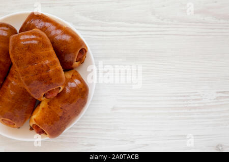 Saucisse de boeuf maison kolache sur une plaque blanche sur une surface en bois blanc, vue du dessus. Copier l'espace. Banque D'Images