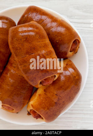 Saucisse de boeuf maison kolache sur une plaque blanche sur un fond de bois blanc, vue du dessus. Close-up. Banque D'Images