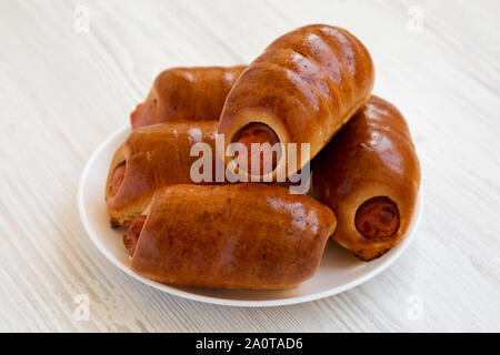 Saucisse de boeuf maison kolache sur une plaque blanche sur une surface en bois blanc, vue de côté. Close-up. Banque D'Images