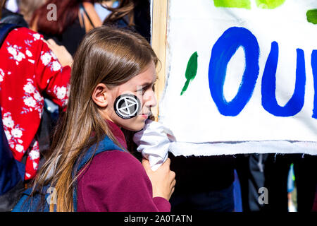 20 septembre 2019, Londres, Royaume-Uni - Jeune fille avec une rébellion Extinction autocollant sur son visage tenant une bannière dans le climat mondial grève dans Westminster Banque D'Images