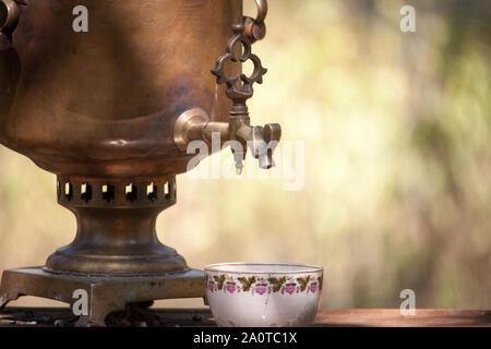 Samovar en bronze Vintage bois et tasse sur la table, la préparation extérieure rouillée l'eau pour le thé brasserie, selective focus Banque D'Images