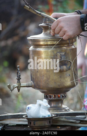 Embrasement de bronze ancien samovar, fixant le bois pour chauffer l'eau pour préparer le thé, selective focus Banque D'Images