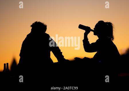 21 septembre 2019, Berlin, Cologne : un homme et une femme s'asseoir au crépuscule sur les rives du Rhin et de boire des bouteilles. Photo : Marius Becker/dpa Banque D'Images