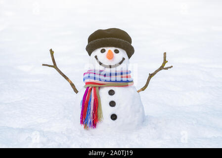 Carte de Noël. Drôle de bonhomme avec un foulard rayé brillant sur fond de neige blanche Banque D'Images