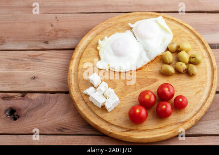 Des œufs au plat, œufs brouillés, fromage, olives et tomates sur plateau en bois sur fond de bois. Le turc, le petit-déjeuner méditerranéen Banque D'Images