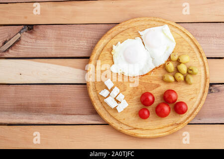 Des œufs au plat, œufs brouillés, fromage, olives et tomates sur plateau en bois sur fond de bois. Le turc, le petit-déjeuner méditerranéen Banque D'Images