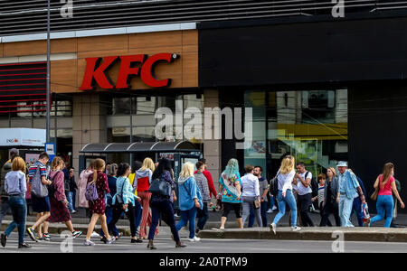 Bucarest, Roumanie - le 19 septembre 2019 : Beaucoup de femmes habillées dans des vêtements colorés traverser la rue à proximité d'un restaurant KFC du rez-de-chaussée de l'Uni Banque D'Images