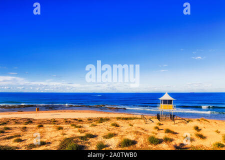 Plage de sable à distance sur la côte du Pacifique de l'Australie avec maître nageur et d'observation life savers watch hut surplombant les amateurs de plage à vagues d'ouvrir Banque D'Images