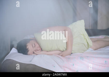 Peu de sommeil relaxant caucasien enfant couché épais avec oreiller vert pendant le sommeil profond en matin sur grand lit dans la chambre Banque D'Images