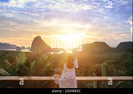 Femme à la robe blanche s'asseoir et voir la montagne tôt le matin à Samet Nangshe point de vue dans la mer d'Andaman sur matin, ciel nuageux, Banque D'Images