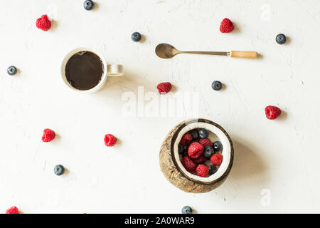 Mise à plat de la nourriture. Les baies fraîches et de noix de coco, tasse de café allongé sur fond gris Banque D'Images