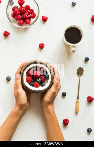 Mise à plat de la nourriture. Les baies fraîches et de noix de coco, tasse de café, les mains Banque D'Images