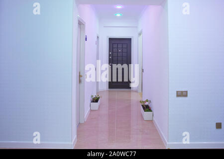 Murs blancs et porte dans couloir avec plancher en bois . Photo de carré long home couloir avec portes et armoire . lumière rose .Porte de l'intérieur de l'espace Banque D'Images