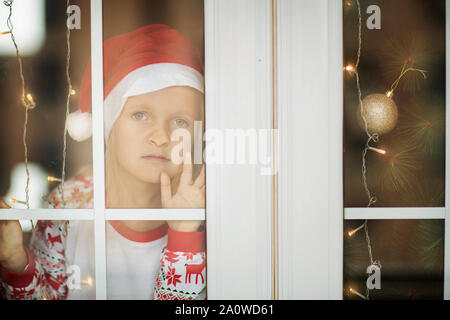 Jolie petite fille avec de longs cheveux blonds en pyjama de Noël à la maison. Décorations de Noël autour de. Heureux moments de la petite enfance. Vacances d'hiver concept Banque D'Images