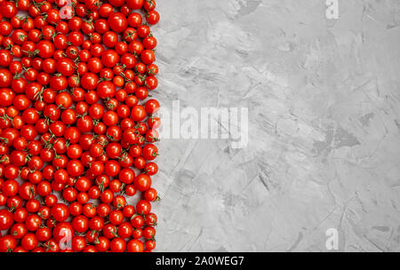 Tomate cerise sur un fond gris. Mise à plat, vue du dessus. Banque D'Images