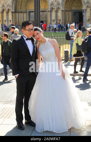 Un couple chinois se faire prendre en photos en face de l'abbaye de Westminster, London, UK Banque D'Images