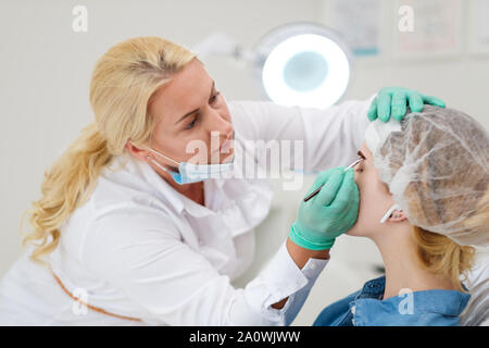 Maquilleur applique de la peinture sur les sourcils de henné dans un salon de beauté. Banque D'Images