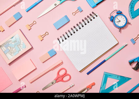 Mise à plat bleu et rose avec des fournitures scolaires et l'ordinateur portable blanc isolé sur pink Banque D'Images