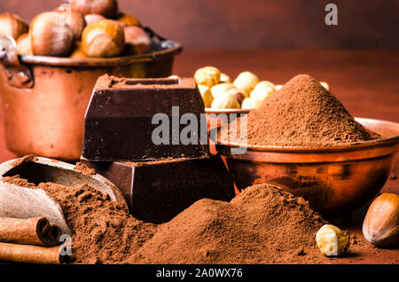 Ingrédients avec la poudre de cacao, noisettes, épices, et morceaux de chocolat noir Banque D'Images