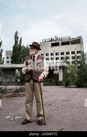 PRIPYAT, UKRAINE - le 15 août 2019 : senior man holding photo canne près du bâtiment avec l'hôtel polissya lettres Banque D'Images