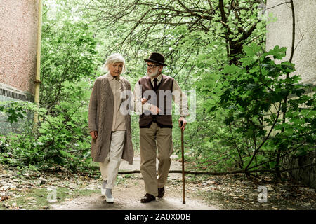 Femme et homme senior retraité avec canne autour de vert des arbres Banque D'Images