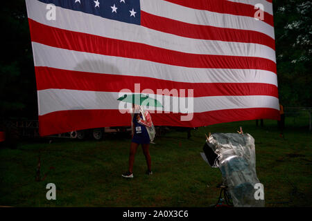 Des Moines, États-Unis. Sep 21, 2019. Une femme passe devant un drapeau américain au cours de la Comté de Polk Steak frite à l'eau Travaux publics Park à Des Moines, Iowa.L'événement a attiré 17 candidats à l'investiture démocrate pour la présidence des États-Unis. Le Caucase de l'Iowa sont Lundi 3 février 2020, et bien que pas un des principaux vous permettront de limiter le domaine de candidats à la présidence avant la première élection primaire dans l'état du New Hampshire. Credit : SOPA/Alamy Images Limited Live News Banque D'Images